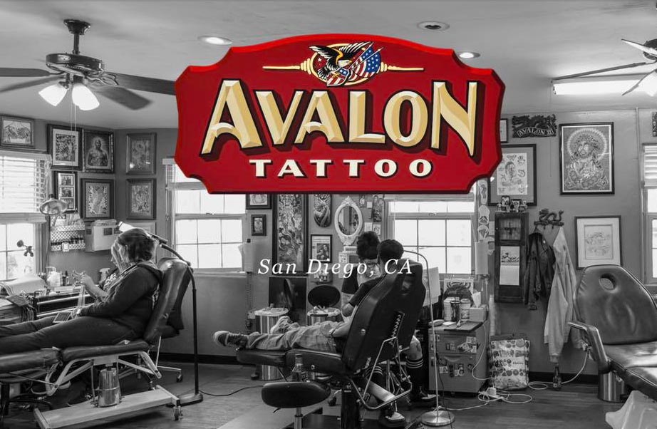 Avalon Tattoo II studio in San Diego, featuring artists working on clients in a traditional tattoo parlor setting with framed artwork on the walls.