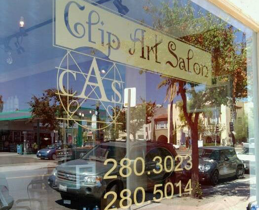 Clip Art Salon storefront on Adams Avenue, San Diego, with reflection of cars and trees in the glass window.