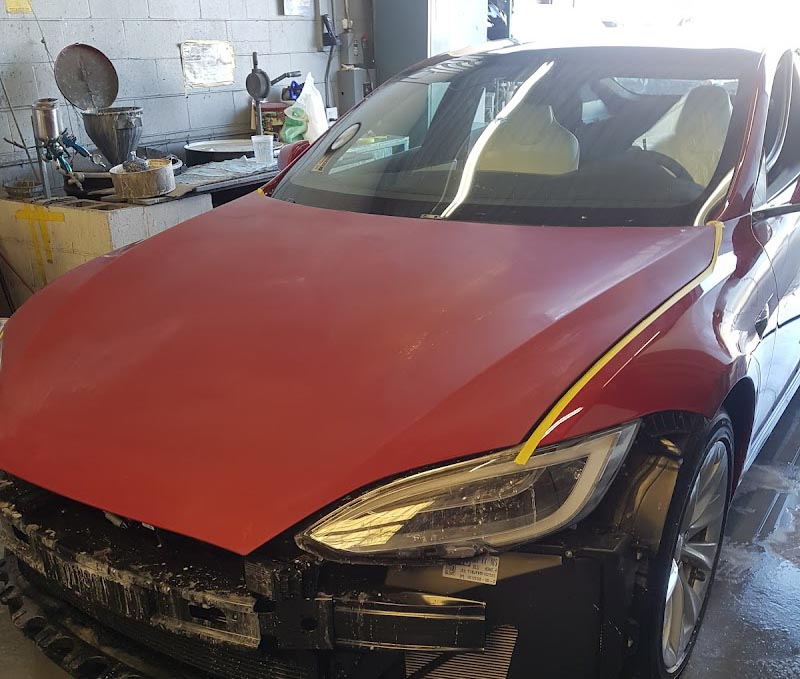 Damaged red Tesla undergoing professional car repair in Adams Avenue, San Diego.