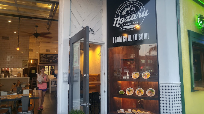 Exterior of Nozaru Ramen Bar in San Diego, showcasing its inviting entrance, stylish signage, and food display.