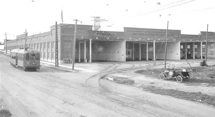 A historic image of a trolley car outside a trolley barn