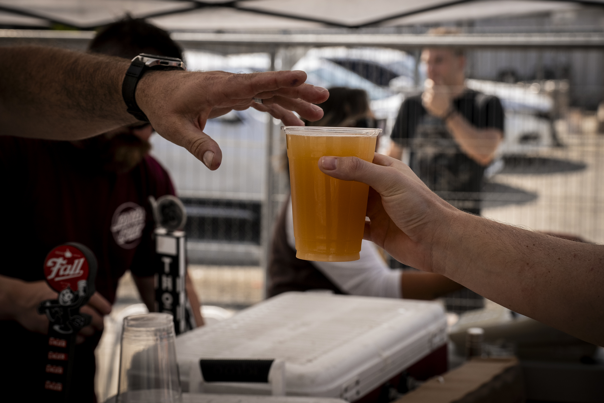 A person hands another person a beer at the Street Fair